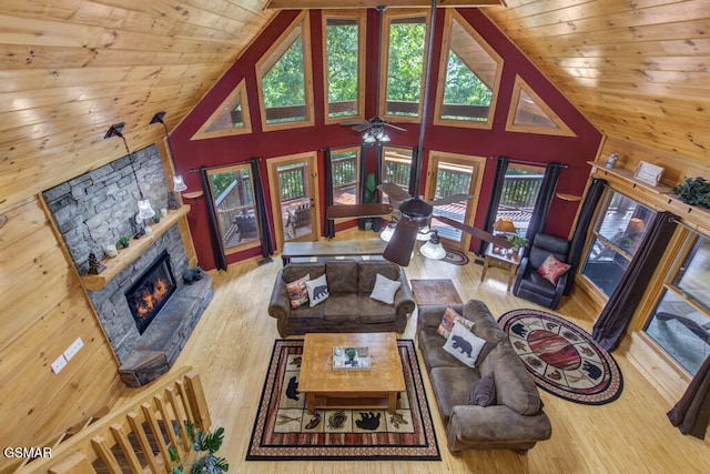 living room featuring hardwood / wood-style flooring, a stone fireplace, wooden ceiling, and a healthy amount of sunlight