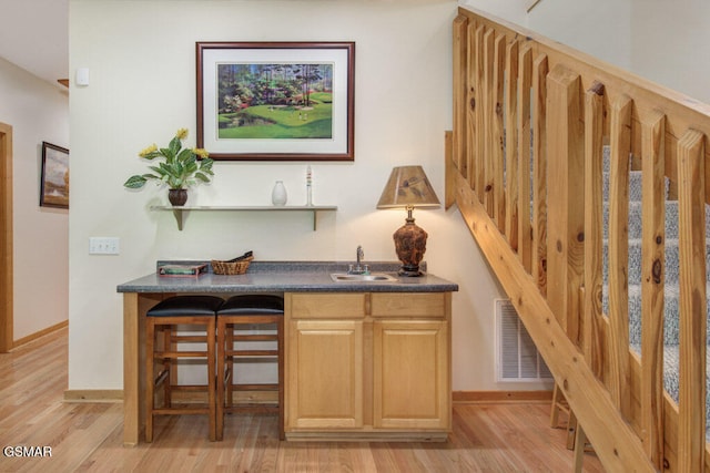 bar featuring sink, light hardwood / wood-style flooring, and light brown cabinets