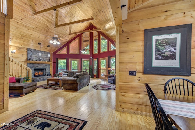 living room with wood ceiling, hardwood / wood-style floors, a stone fireplace, and wooden walls