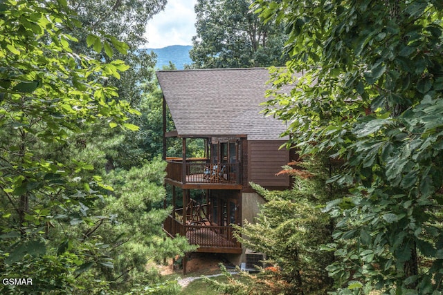 rear view of house featuring a balcony and a deck with mountain view