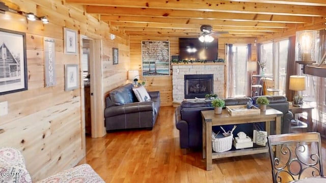 2022 Starr Crest Dr, Sevierville, TN 37876 - living area with beamed ceiling, hardwood / wood-style flooring, wood walls, ceiling fan, and a stone fireplace