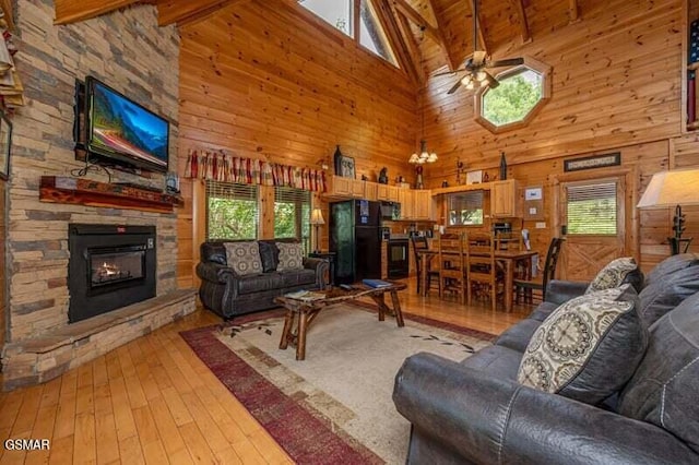 living room with a ceiling fan, light wood-type flooring, a wealth of natural light, and a stone fireplace