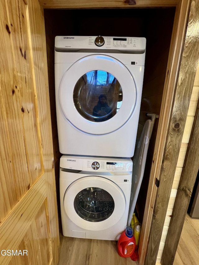 laundry area with wood-type flooring and stacked washing maching and dryer