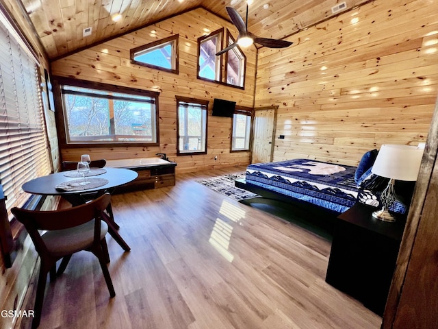 bedroom with wood walls, light hardwood / wood-style floors, wooden ceiling, and high vaulted ceiling