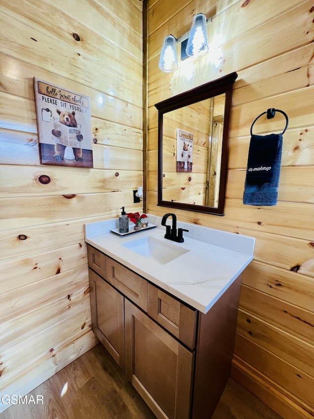 bathroom featuring hardwood / wood-style flooring, vanity, and wood walls