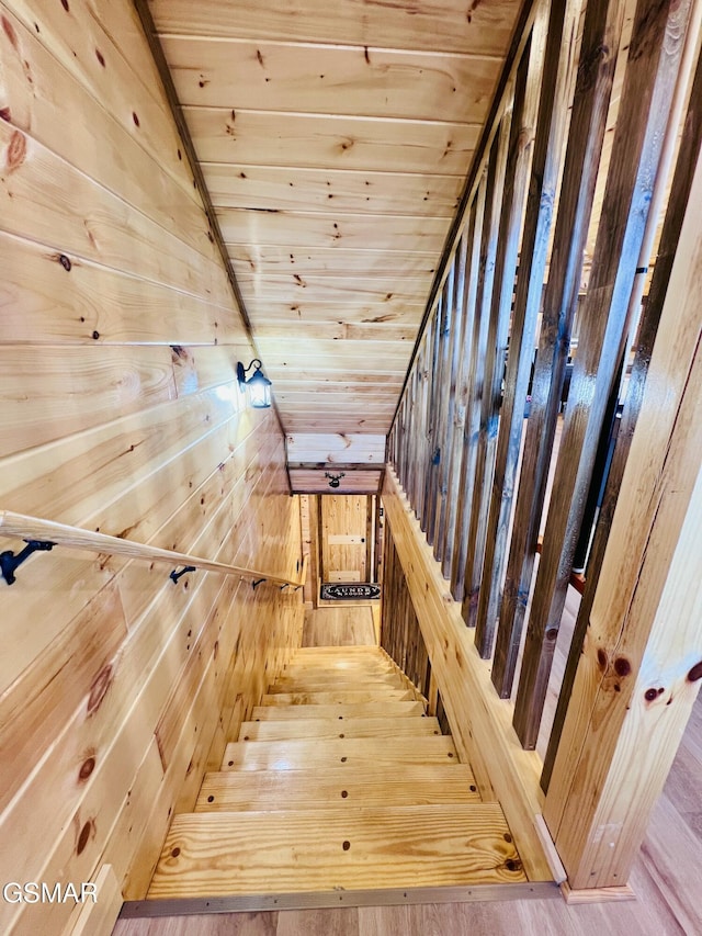 staircase with wood-type flooring, lofted ceiling, wood walls, and wood ceiling