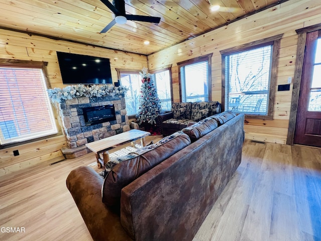 living room with ceiling fan, wooden ceiling, light hardwood / wood-style floors, wooden walls, and a fireplace