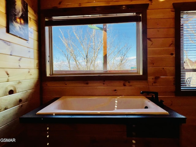 bathroom featuring wood walls, plenty of natural light, and a washtub