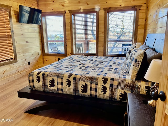 bedroom with hardwood / wood-style floors and wooden walls