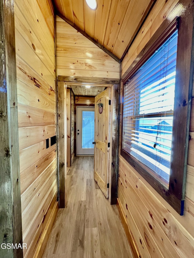 corridor with light hardwood / wood-style flooring, wood ceiling, lofted ceiling, and wood walls