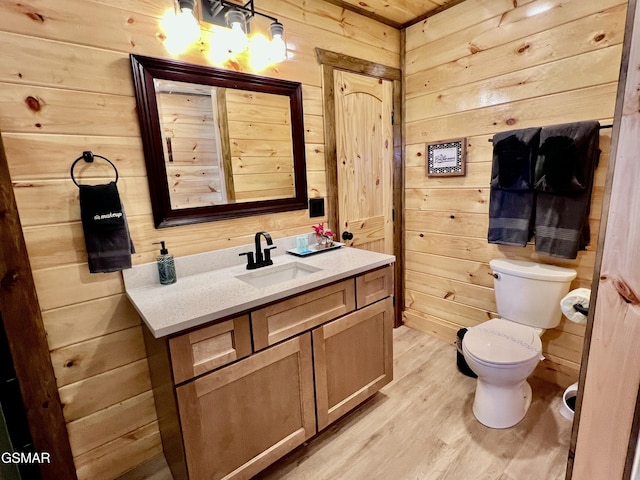 bathroom with wooden walls, toilet, vanity, and hardwood / wood-style flooring