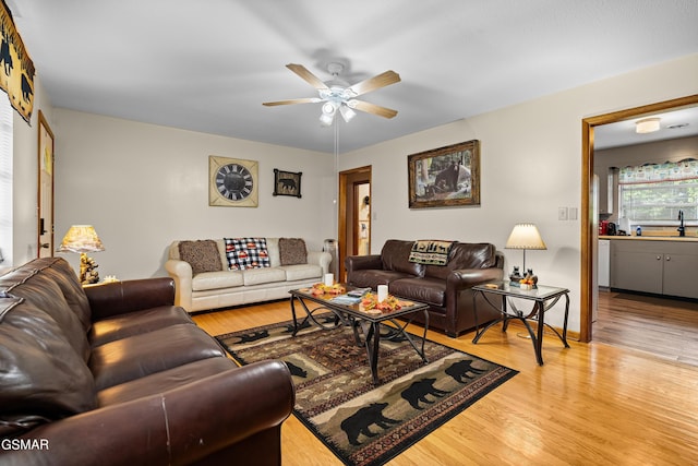 living room featuring ceiling fan, sink, and light hardwood / wood-style floors