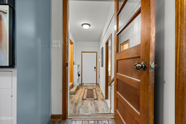 hallway featuring wood walls, ornamental molding, and hardwood / wood-style flooring