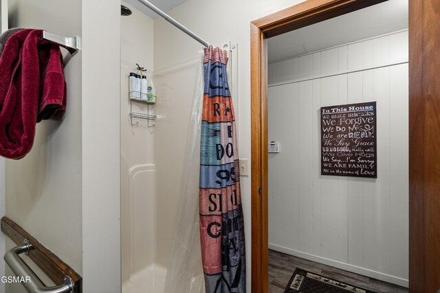 bathroom featuring wood walls, wood-type flooring, and a shower with shower curtain