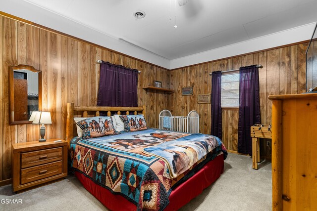 bedroom featuring light carpet, ceiling fan, and wooden walls