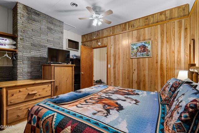 carpeted bedroom with ceiling fan and wooden walls