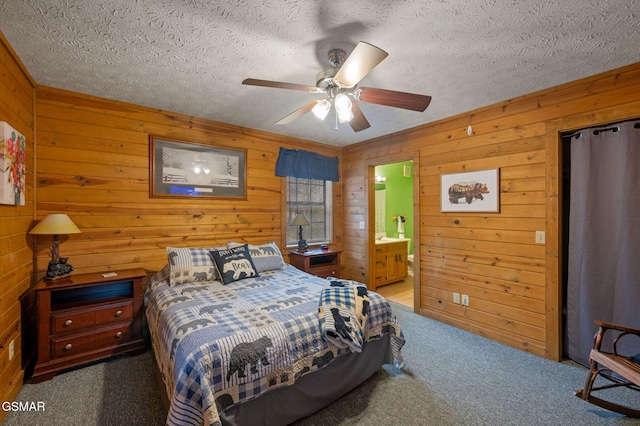 bedroom featuring ceiling fan, connected bathroom, a textured ceiling, and dark colored carpet