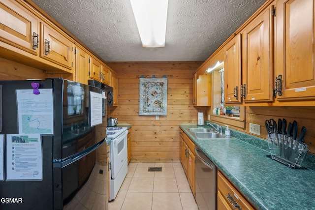 kitchen featuring sink, light tile patterned floors, wooden walls, black appliances, and a textured ceiling