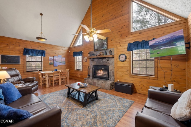 living room featuring a healthy amount of sunlight, a stone fireplace, and light hardwood / wood-style flooring