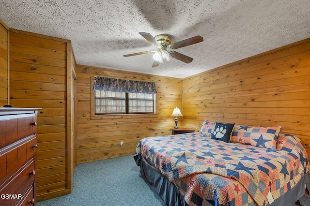 bedroom featuring ceiling fan, carpet floors, wooden walls, and a textured ceiling