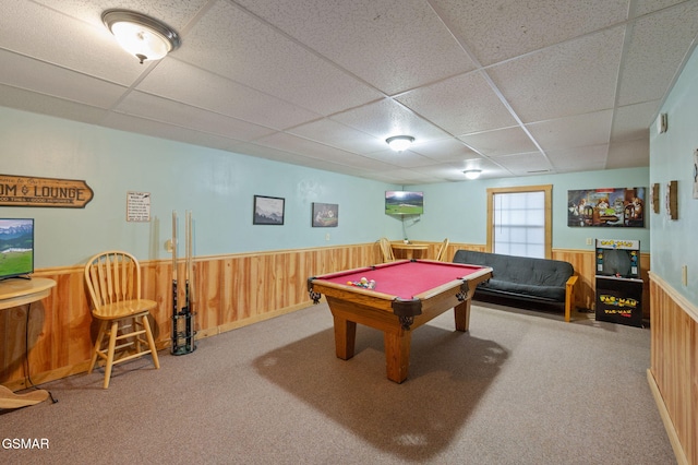 recreation room featuring carpet floors, a drop ceiling, and wood walls