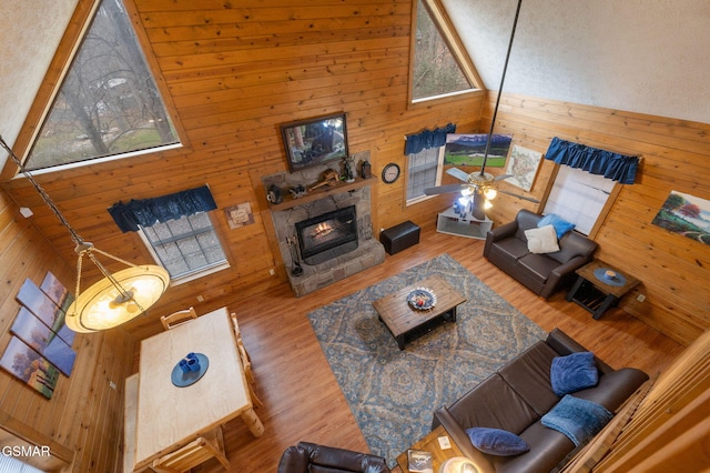 living room featuring wooden walls, a fireplace, high vaulted ceiling, and hardwood / wood-style floors