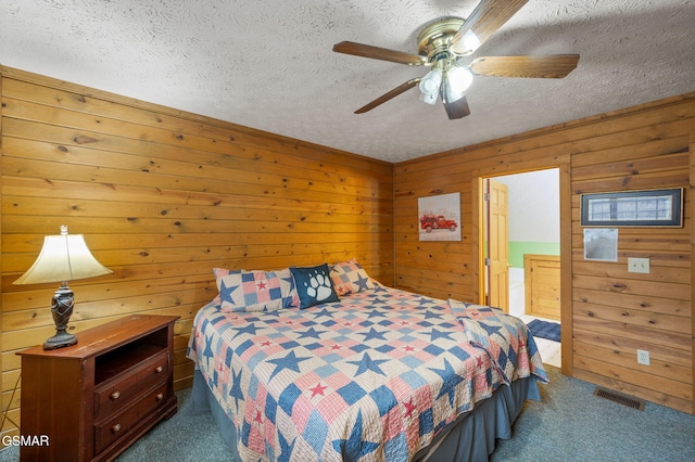 bedroom featuring ceiling fan, carpet floors, a textured ceiling, and wood walls