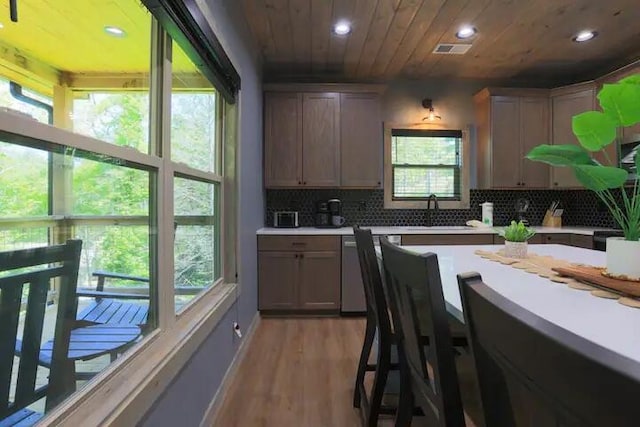 kitchen with plenty of natural light, light hardwood / wood-style flooring, decorative backsplash, and wooden ceiling