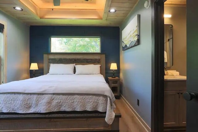 bedroom with a raised ceiling and wood-type flooring