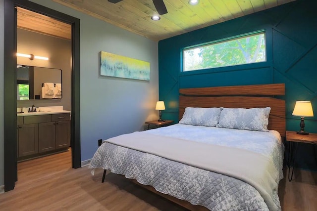 bedroom with ensuite bath, sink, light hardwood / wood-style flooring, and wooden ceiling