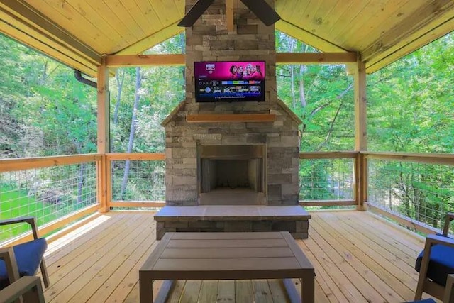 unfurnished sunroom with wood ceiling, plenty of natural light, vaulted ceiling, and an outdoor stone fireplace