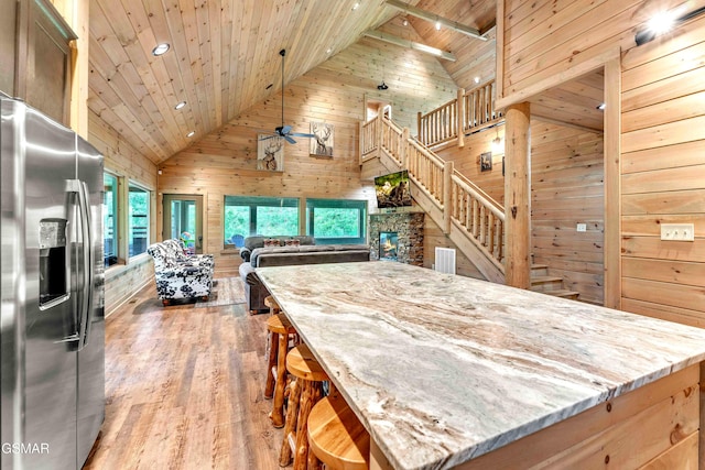 kitchen featuring stainless steel fridge, wooden walls, wood ceiling, high vaulted ceiling, and ceiling fan