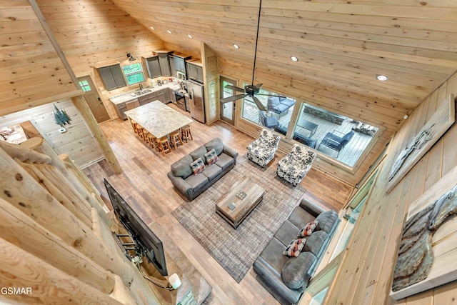 living room with wood ceiling, wood walls, light wood-style floors, and high vaulted ceiling