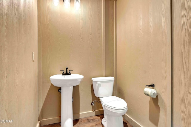 bathroom featuring toilet, wood finished floors, baseboards, and a sink