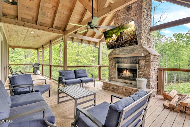deck featuring an outdoor living space with a fireplace, a forest view, a grill, and ceiling fan