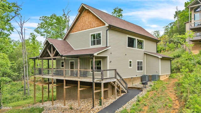 rear view of house with central air condition unit, roof with shingles, stairs, and a wooden deck