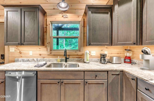 kitchen featuring dishwasher, a sink, and light stone countertops