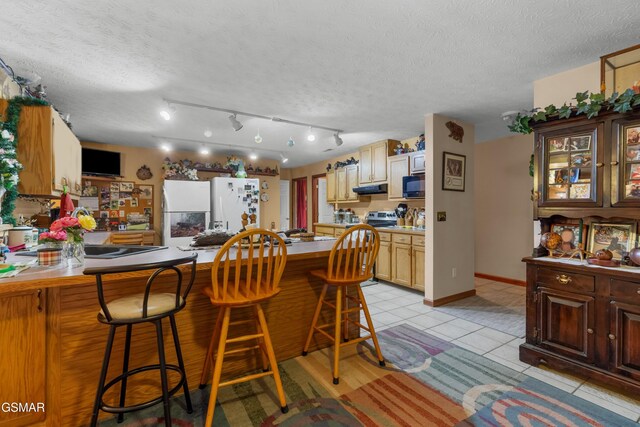 1878 Omaha Rd, Del Rio, TN 37727 - kitchen featuring freestanding refrigerator, black microwave, a breakfast bar, a peninsula, and light tile patterned floors