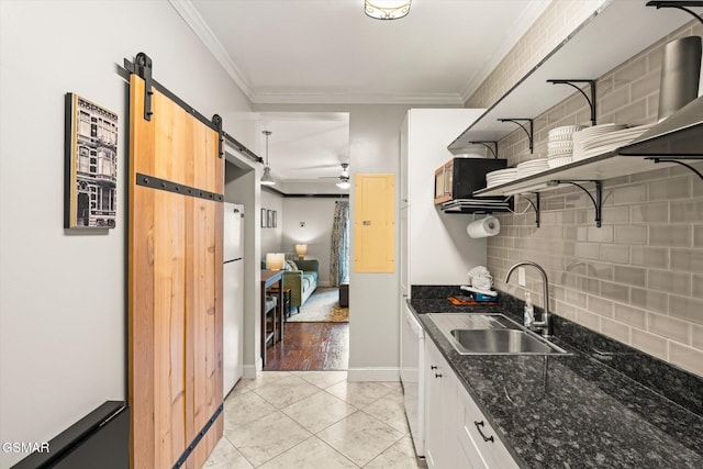 kitchen featuring ceiling fan, sink, a barn door, crown molding, and white cabinets