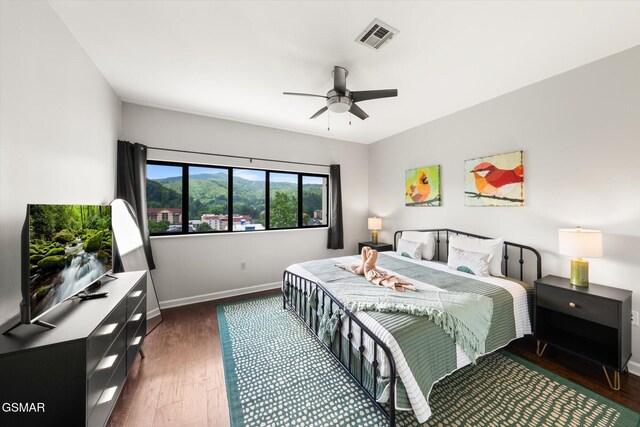 bedroom with dark hardwood / wood-style flooring and ceiling fan