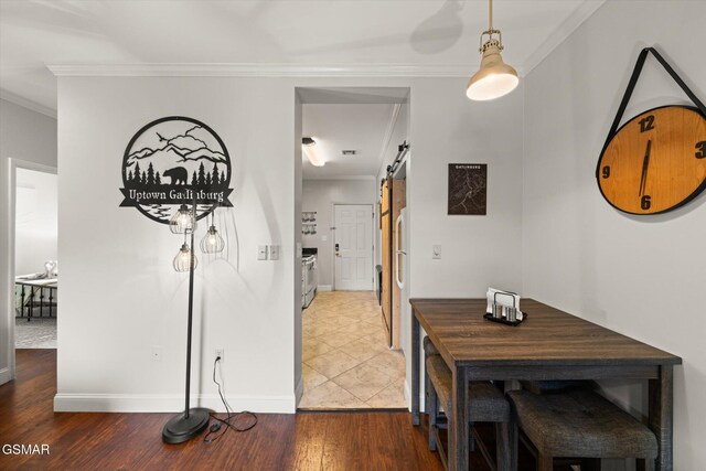 interior space with a barn door, wood-type flooring, and ornamental molding