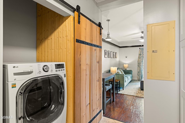 washroom featuring hardwood / wood-style floors, electric panel, ceiling fan, a barn door, and washer / clothes dryer