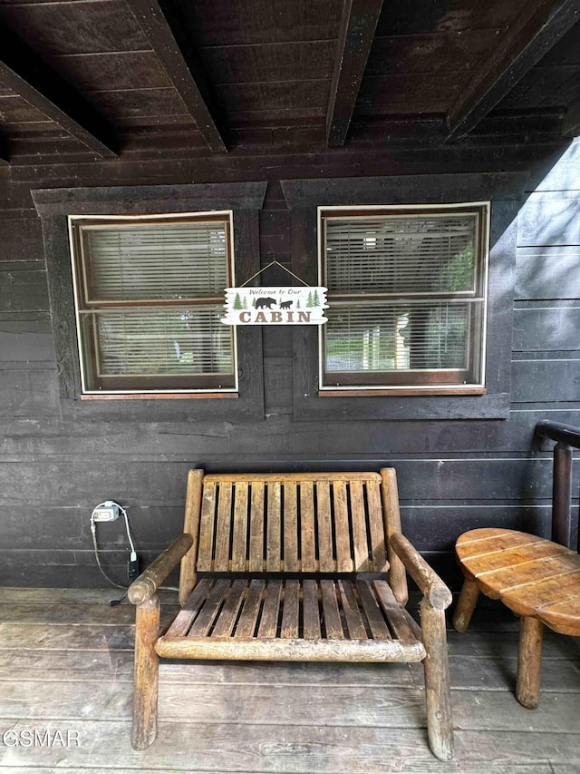 exterior space featuring wooden walls, beamed ceiling, and wooden ceiling