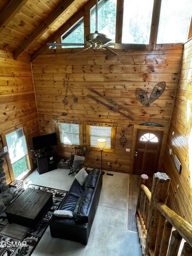 living room with vaulted ceiling with beams, wood walls, ceiling fan, and wood ceiling