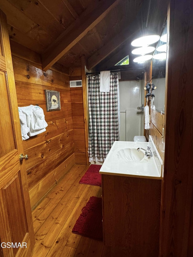 bathroom featuring wooden ceiling, beamed ceiling, hardwood / wood-style floors, wooden walls, and vanity