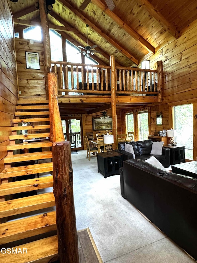 carpeted living room with beamed ceiling, high vaulted ceiling, wooden ceiling, and wood walls