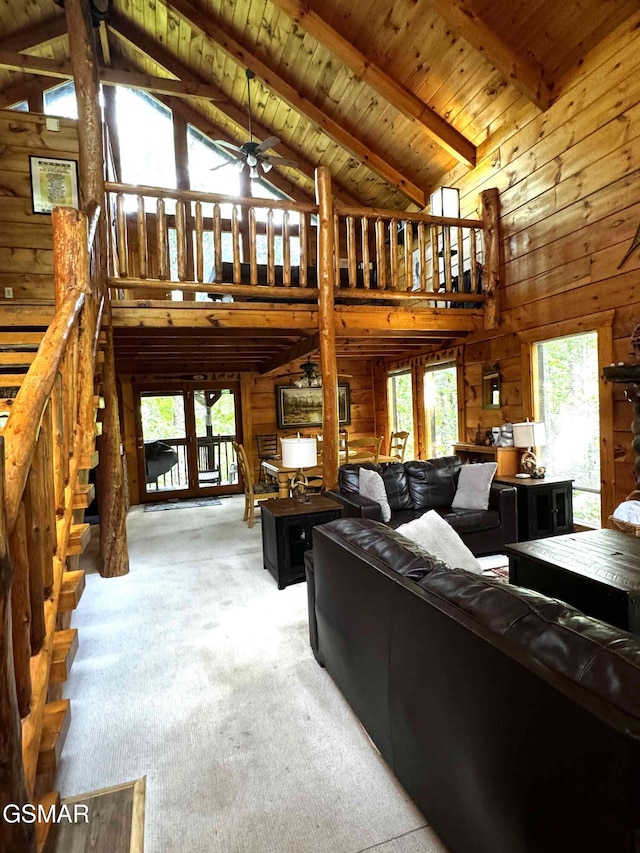 carpeted living room featuring wood ceiling, ceiling fan, beam ceiling, high vaulted ceiling, and wood walls