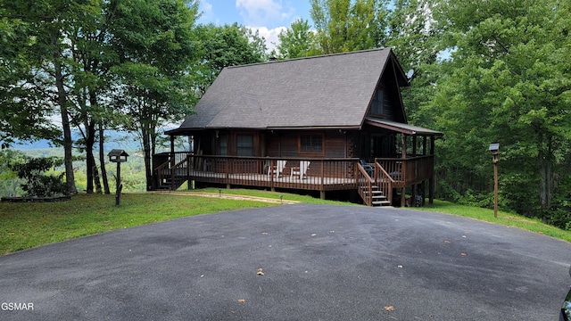 view of front of home featuring a shingled roof, driveway, and a front lawn