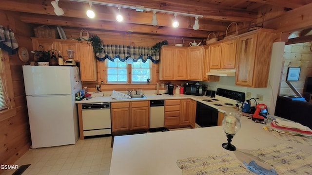 kitchen featuring white appliances, wooden walls, light countertops, under cabinet range hood, and a sink