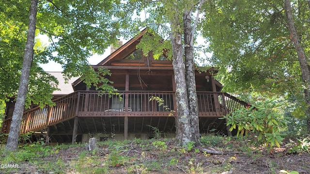 back of house with a wooden deck, a chimney, and a sunroom